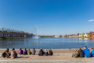 People relaxing at the steps of the Pfaffenteich lake in Schwerin, Germany clipart