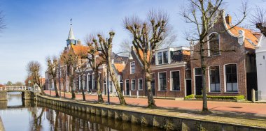 Panorama of historic town hall and old houses at the canal in Balk, Netherlands clipart