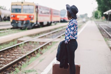 Tren istasyonunda çantalı kırmızı ceketli genç bir kadın.