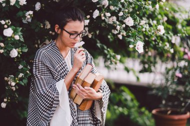 Ellerinde çiçeklerle gözlüklü yakışıklı adam.