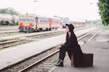 Tren istasyonunda poz veren kırmızı ceketli genç bir kadın.