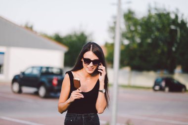 Güneş gözlüklü genç bir kadın sokakta poz veriyor.