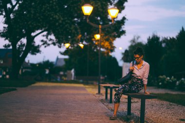 Parkta bir buket çiçekle siyah elbiseli güzel genç bir kadın.