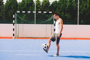 Delikanlı stadyumda futbol oynuyor.
