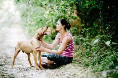 Parkta köpeklerle oynayan genç bir kadın