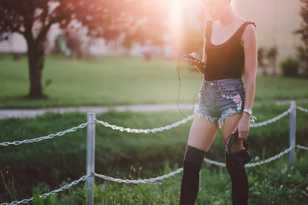 公園で音楽を聴くヘッドフォンを持つ若い女性 — ストック写真