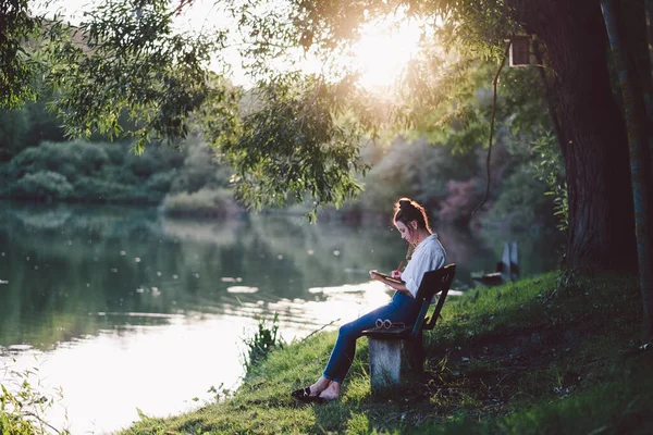 年轻女子坐在草地上看书 — 图库照片