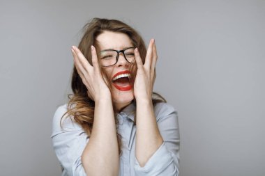 Gri arka planda gözlüklü çılgın iş kadını