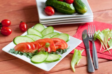 Dilimlenmiş domates ve salatalıklar bir tabakta yatıyor.