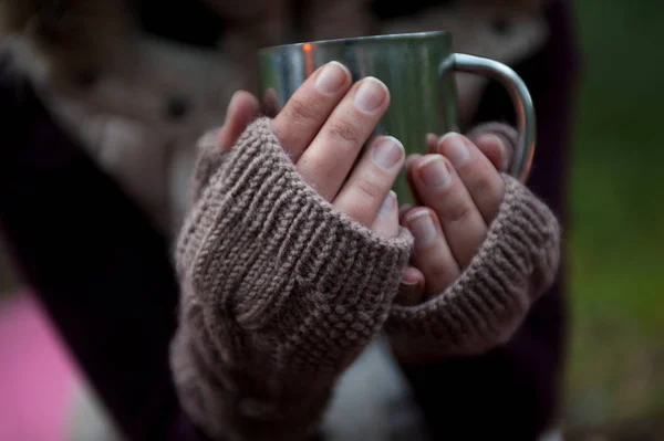 Kovový hrnek s horkým čajem v ruce v teple útulné palčáky — Stock fotografie