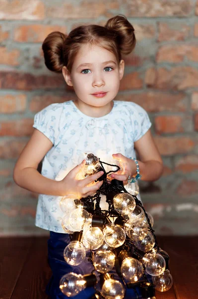 Little girl with bright christmas garland in her hand — Stock Photo, Image