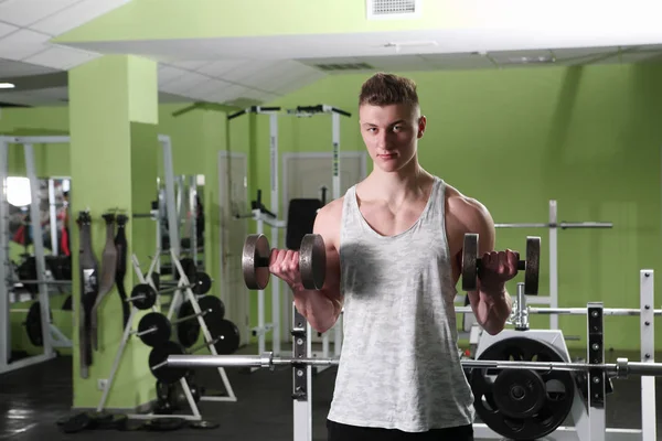 Der junge Mann trainiert im Fitnessstudio — Stockfoto