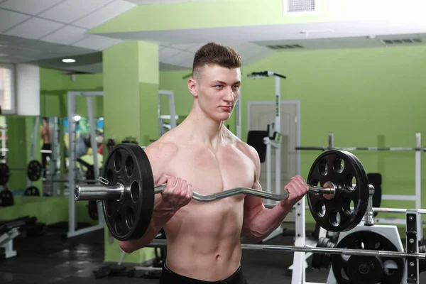 Der junge Mann trainiert im Fitnessstudio — Stockfoto
