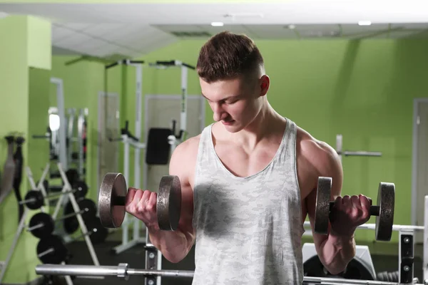 Der junge Mann trainiert im Fitnessstudio — Stockfoto