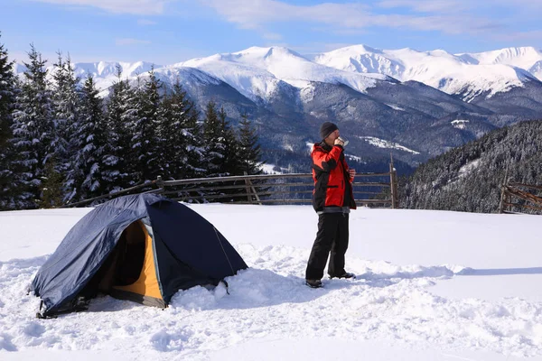 Турист пьет чай у палатки в зимних горах . — стоковое фото