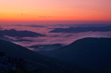 Dağlarda gün doğumu. Güneş, sisle kaplı vadilerin üzerinden doğuyor..