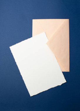 Davetiyeler için şablon, selamlar. Mavi arka planda, beyaz bir sayfa kağıt, bir zarf, bir defter, taşlı bir yüzük ve dekoratif mumlar. Düğün ve doğum günü için minimalist tasarım.