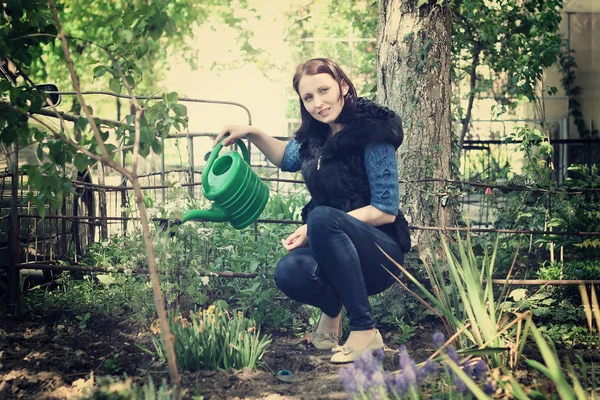 Girl in gardening waters flowers — Stock Photo, Image