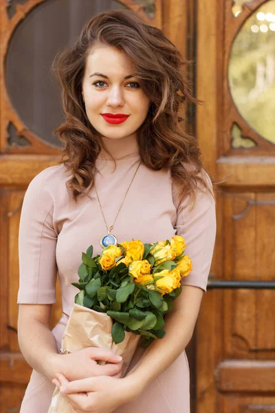 Mulher com rosas de pé perto da porta antiga — Fotografia de Stock