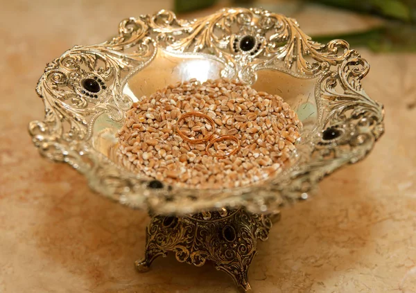 Anillos de boda se encuentran en un plato con granos de trigo —  Fotos de Stock