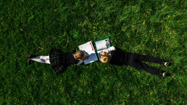 Çocuklar yazın çimlerin üzerinde kitap okuyorlar. Üst görünüm