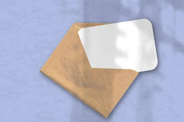 桌上柔软的蓝色背景上有一个信封 上面有一张有纹理的白纸 自然光从窗户投射出阴影 横向方向 — 图库照片