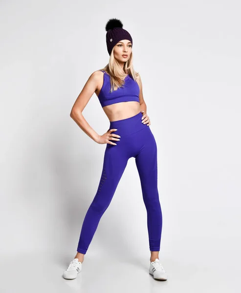 Chica del deporte haciendo ejercicio de pie en azul púrpura ejercicios de ropa deportiva sobre fondo blanco —  Fotos de Stock