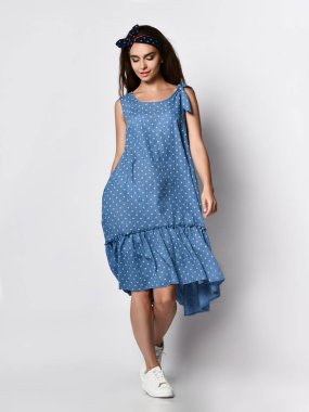 İnce kıvırcık kadın modeli ipek soluk mavi elbise tam büyüme kamera bakıyor. Romantik giysiler içinde sevimli kız bir tarih gidiyor