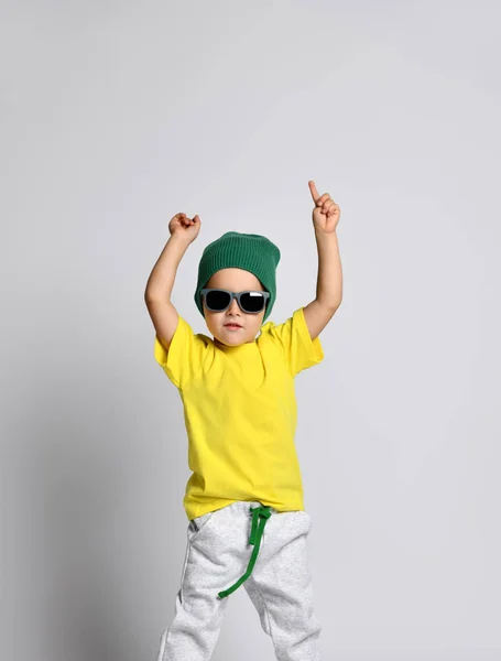 Glad funky barn pojke håller händerna över huvudet fri text kopiera utrymme. Gul T-shirt och grön hatt. — Stockfoto