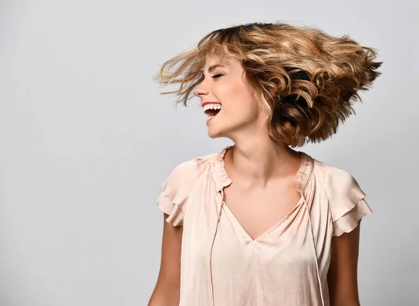 bej kısa kollu saten bluz genç kadın saçları ile başını sallar. Sevinç, mutluluk, neşe, eğlence kavramı.