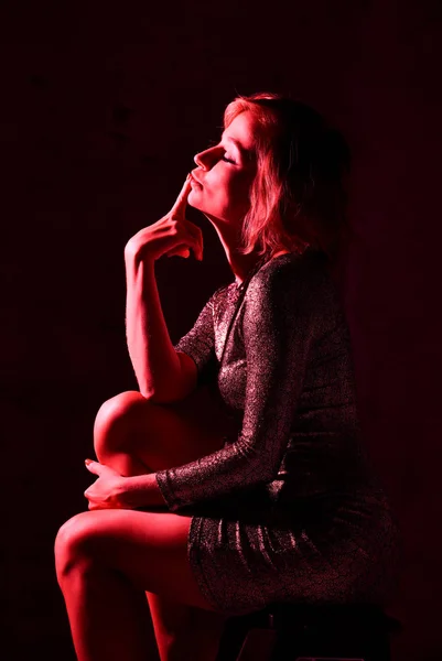 Attraktive junge Mädchen in einem engen, glänzenden Kleid im Studio mit Farbfiltern. — Stockfoto