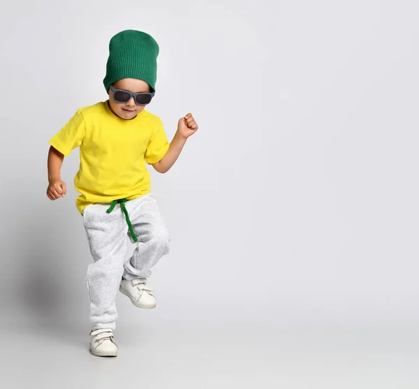 Niño alegre chico hipster en un sombrero verde bailando en pantalones anchos —  Fotos de Stock