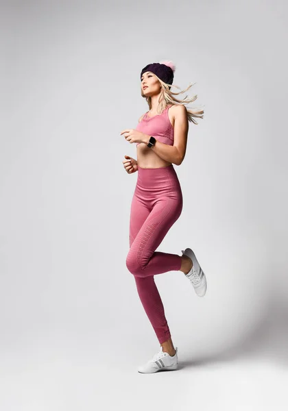 완벽 한 체격의 금발에 건강 한 생활을 하며 스포츠 스타일로 편안 한 분홍색 옷을 입는다. 총 있는 따뜻 한 모자 — 스톡 사진