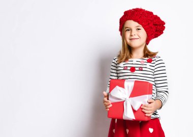 Beyaz kurdeleli kırmızı hediye kutusunu arka planda tutan mutlu genç kız.