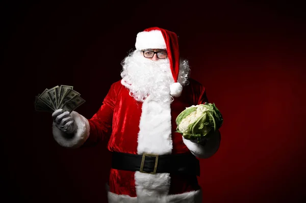 Фото счастливого Санта-Клауса с долларовыми купюрами и капустой, смотрящего в камеру — стоковое фото
