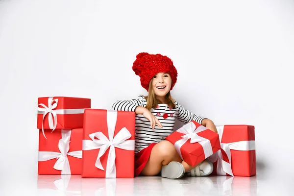 Ευτυχισμένο χαριτωμένο νεαρό κορίτσι κρατώντας ένα κόκκινο κουτί δώρου με μια λευκή κορδέλα πάνω από ένα ελαφρύ φόντο — Φωτογραφία Αρχείου