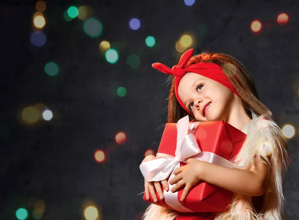 Счастливая маленькая улыбающаяся девочка с красной подарочной коробкой . — стоковое фото