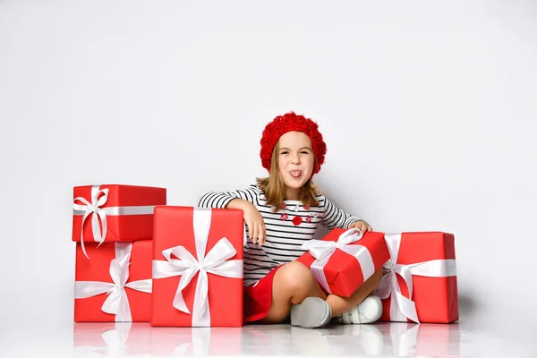 Gelukkig schattig jong meisje holding een rood cadeau doos met een wit lint over een licht achtergrond — Stockfoto