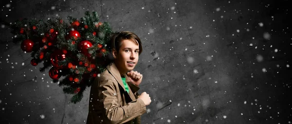 Teen man carrying christmas tree. Christmas, new year, holidays. Christmas decor concept.