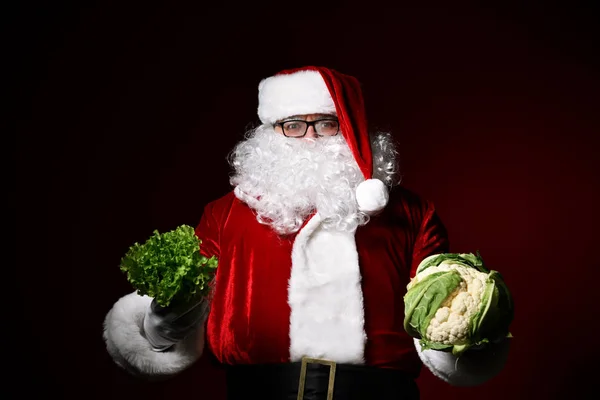 Веселый Санта Клаус держит в одной руке кучу салата в другой качели цветной капусты. Выбор. Приятного рождественского ужина. Здоровые рождественские рецепты. — стоковое фото