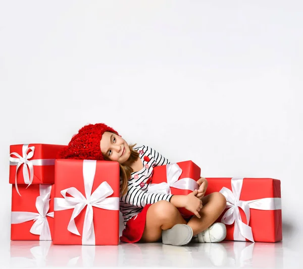 Happy cute young girl holding a red gift box with a white ribbon over a light background — Stock Photo, Image