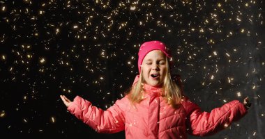 Elleriyle kar tanelerini yakalayan mutlu küçük kız. Koyu arkaplan çocuğu.