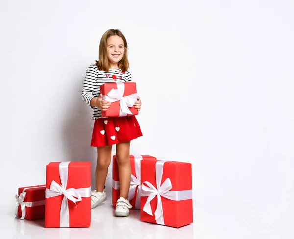 Gelukkig schattig jong meisje holding een rood cadeau doos met een wit lint over een licht achtergrond — Stockfoto