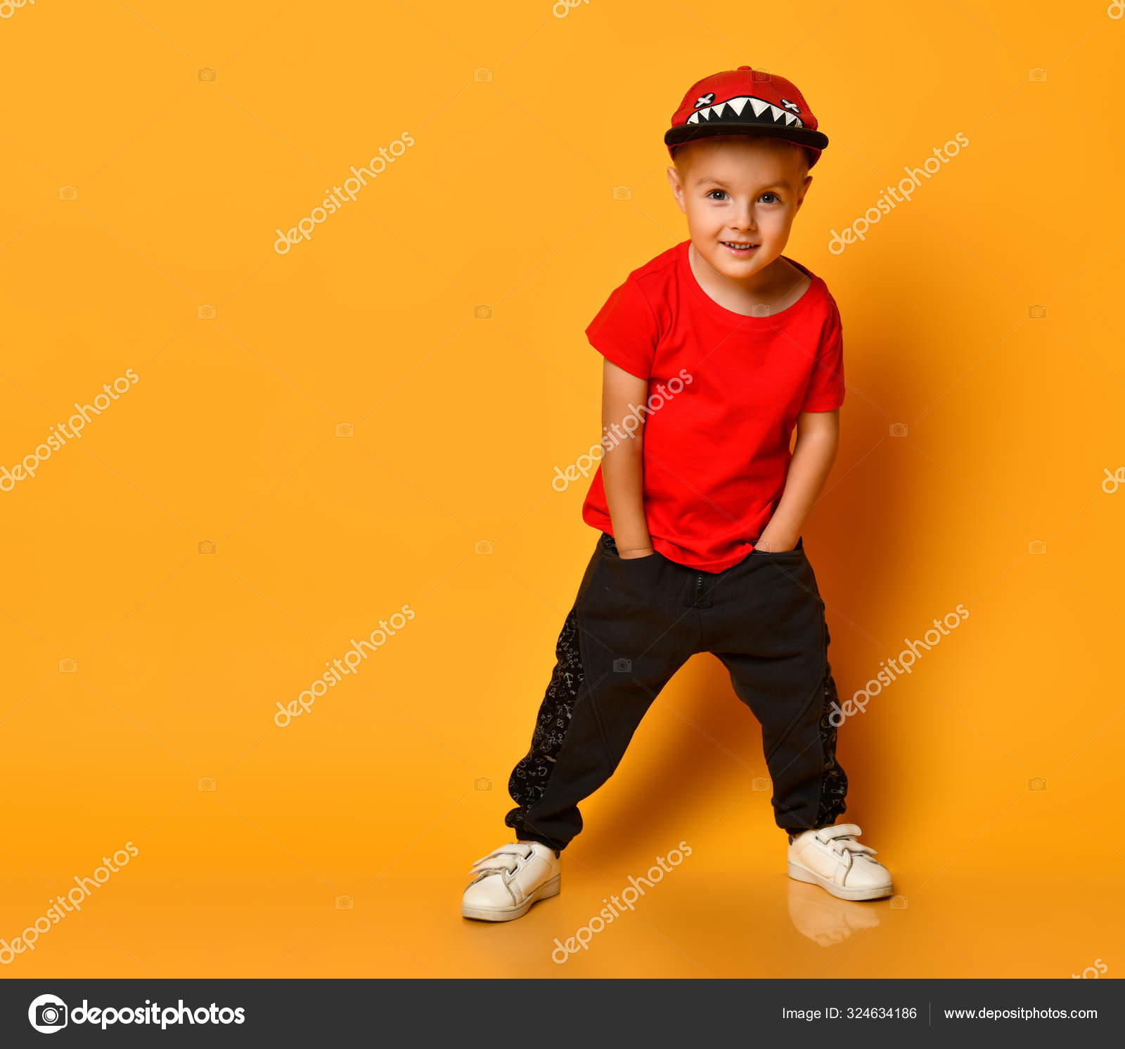 Young guy boy in a red T-shirt and dark pants, white sneakers and a funny cap on a free copy space a yellow background Stock Photo by ©ddkolos.gmail.com 324634186