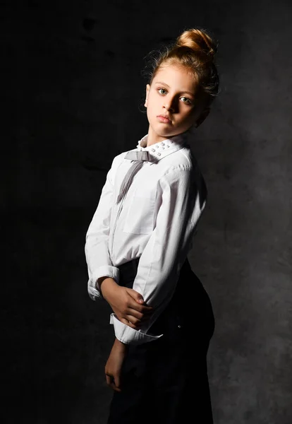 Little female caucasian model posing in school uniform on a gray concrete studio background. — Stock Photo, Image