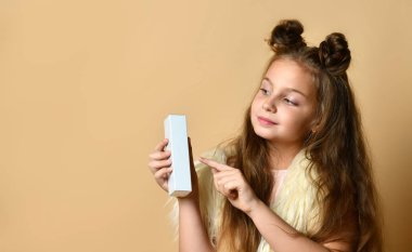 Güzel saç kesimi olan güzel bir kız size içinde krem, parfüm ya da kozmetik ürünler olan bir kutu sunar.