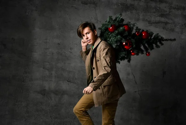 Teen man carrying christmas tree. Christmas, new year, holidays. Christmas decor concept.