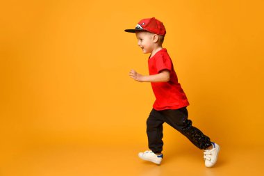 smiling Little boy running left over yellow background clipart