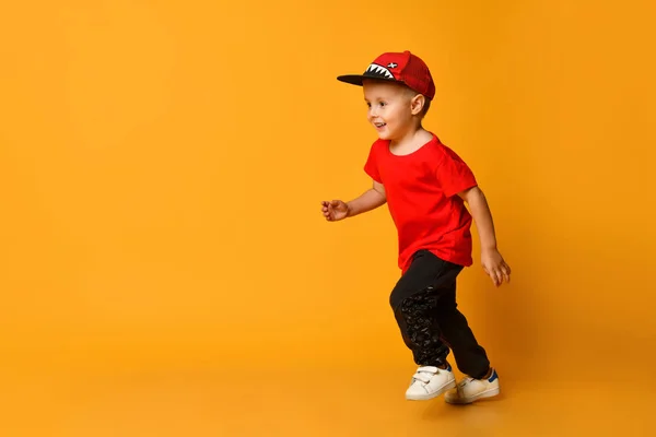 Leende liten pojke kör vänster över gul bakgrund — Stockfoto