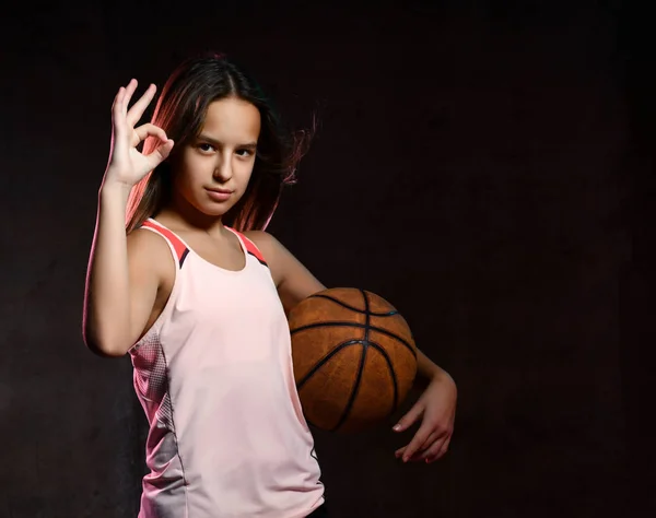 Hermosa mujer adolescente caucásica en ropa deportiva jugando baloncesto. Concepto deportivo aislado sobre fondo negro . — Foto de Stock